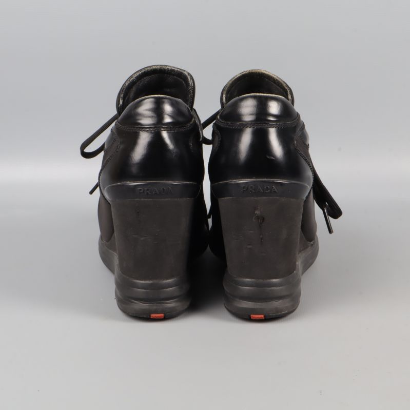 Baksidan av svarta sneakers med kilklack och röd detalj på sulan