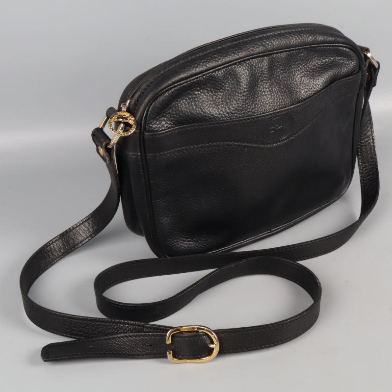 Närbild på svart läderväska med präglad yta och axelrem