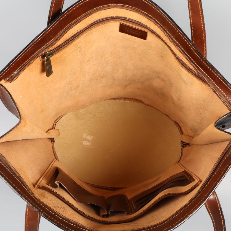 Närbild insida av brun läderväska med fack