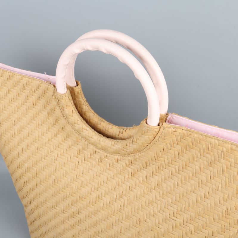 Närbild på väskans ljusrosa plastdetaljer och handtag
