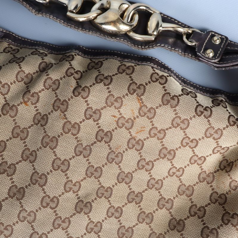 Närbild utfällbar kedjedetalj och läderkant väska