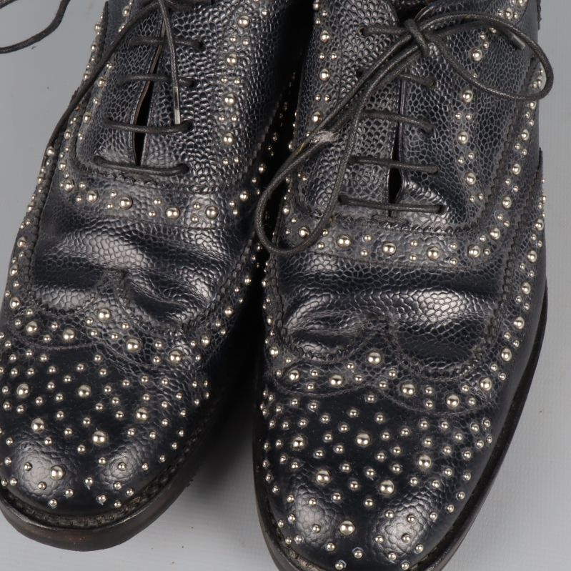Närbild på nitar och mönstrat svart läder på brogues