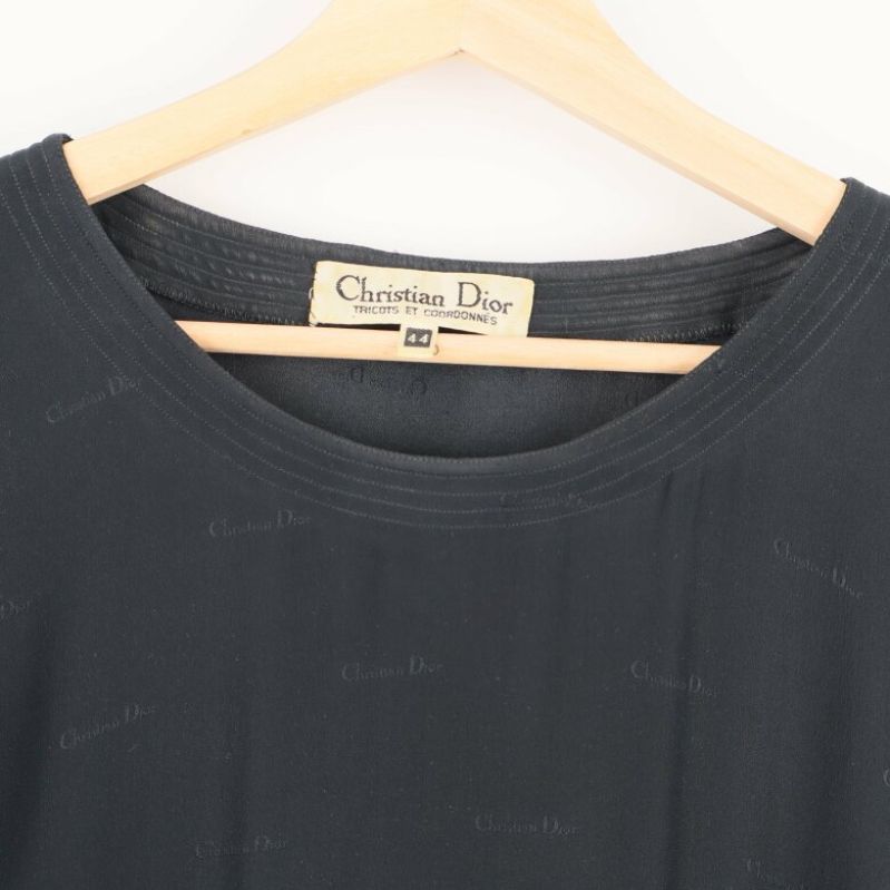 Närbild på Christian Dior-logga vid halsen på svart klänning