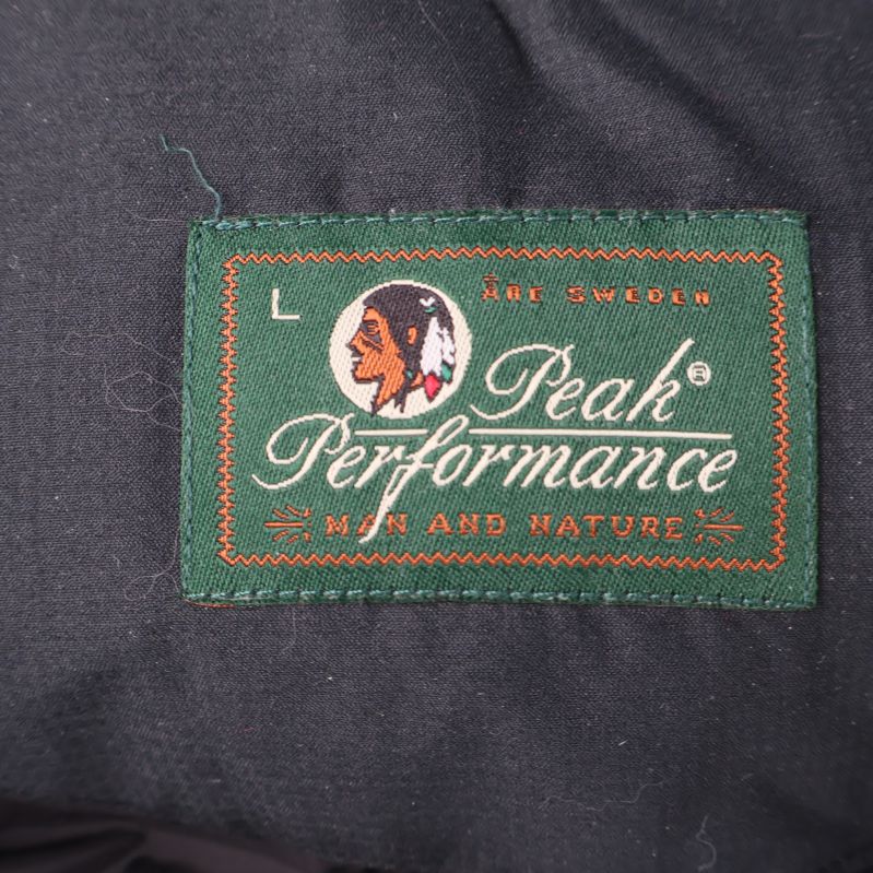 Peak Performance logotyp på grön etikett med storlek L inuti väst