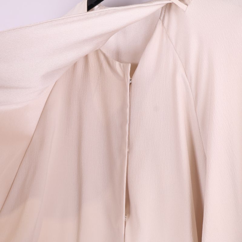 Närbild på insidan av beige omlottblus och sömmar