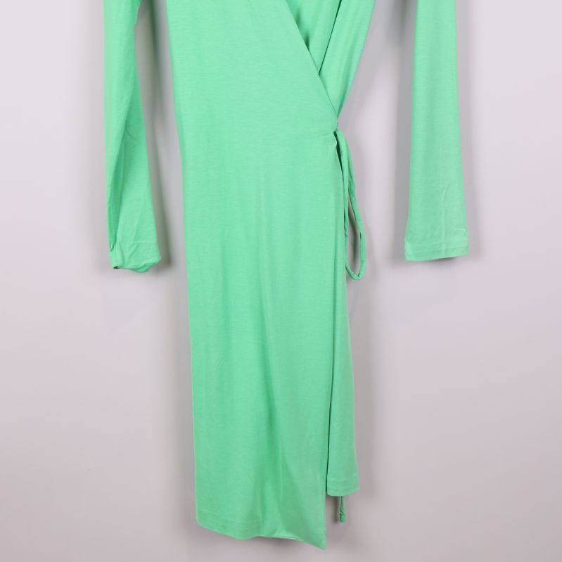 Nedre del av grön omlottklänning med knytband