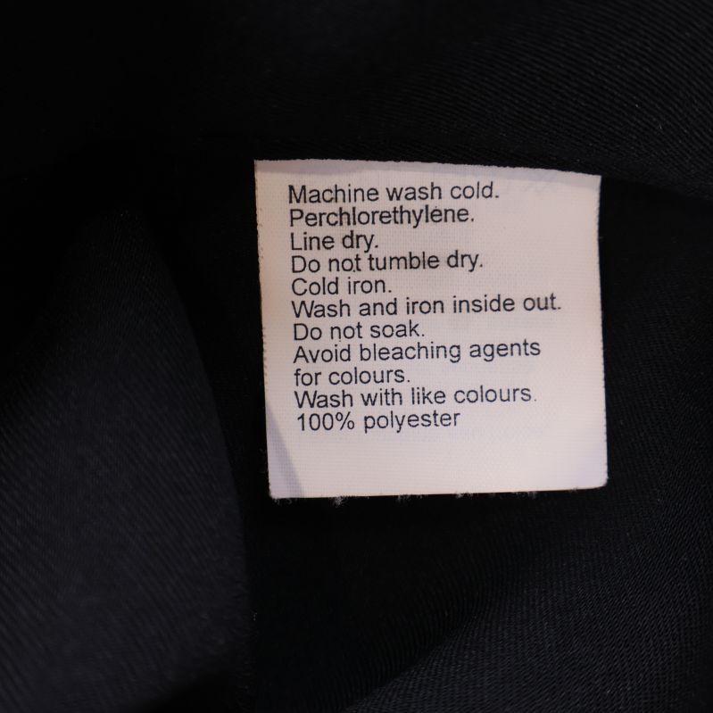 Materialetikett som anger 100% polyester och skötselråd