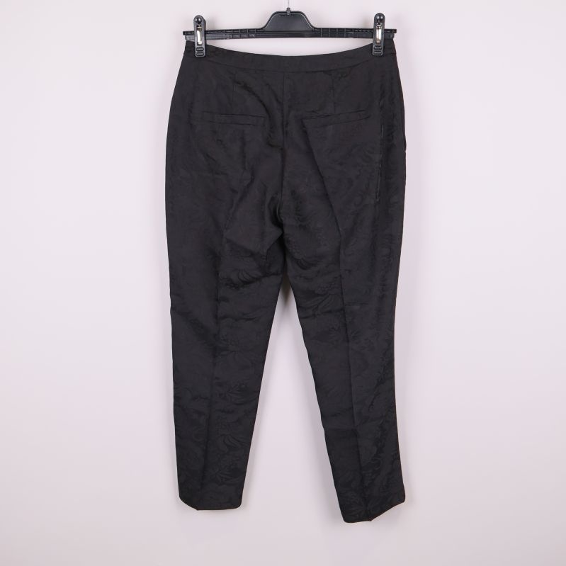 Svarta mönstrade byxor bakifrån på galge mot ljus bakgrund