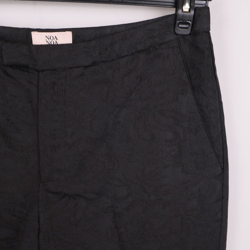 Ficka och liv fram på svarta byxor med subtilt mönster