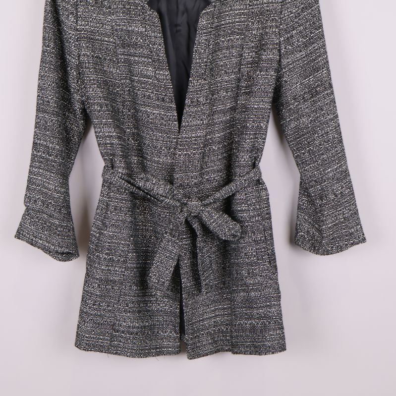 Närbild på nederdelen av svartvit kavaj med knytskärp