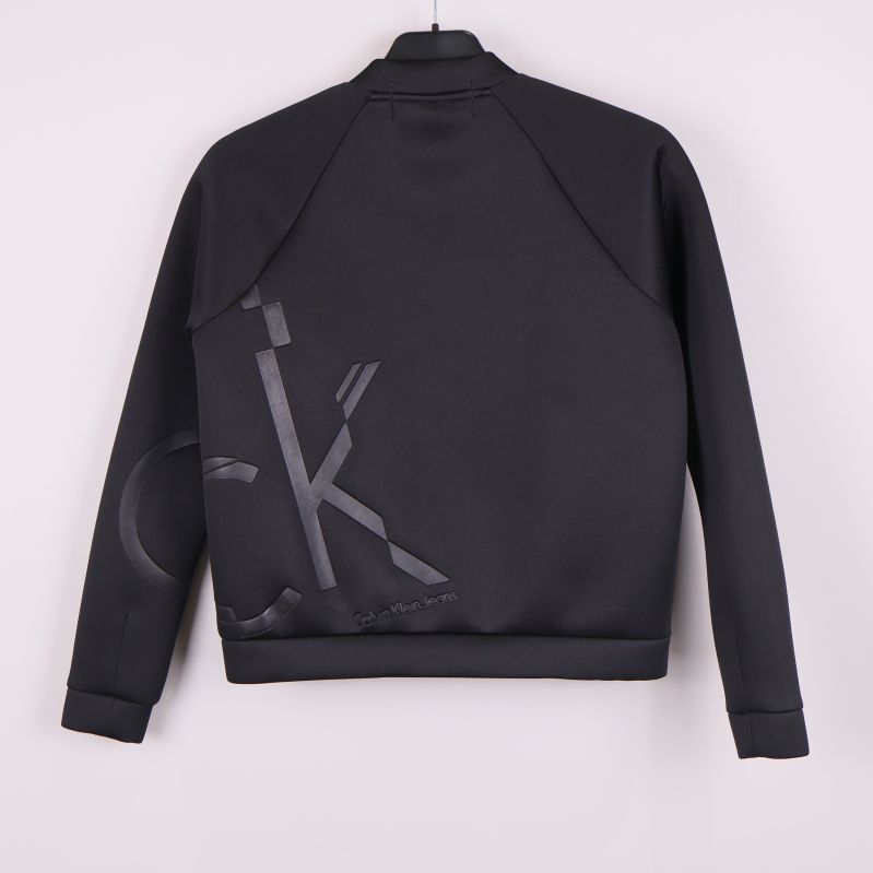 Baksida av svart bomberjacka med stor blank CK-logga