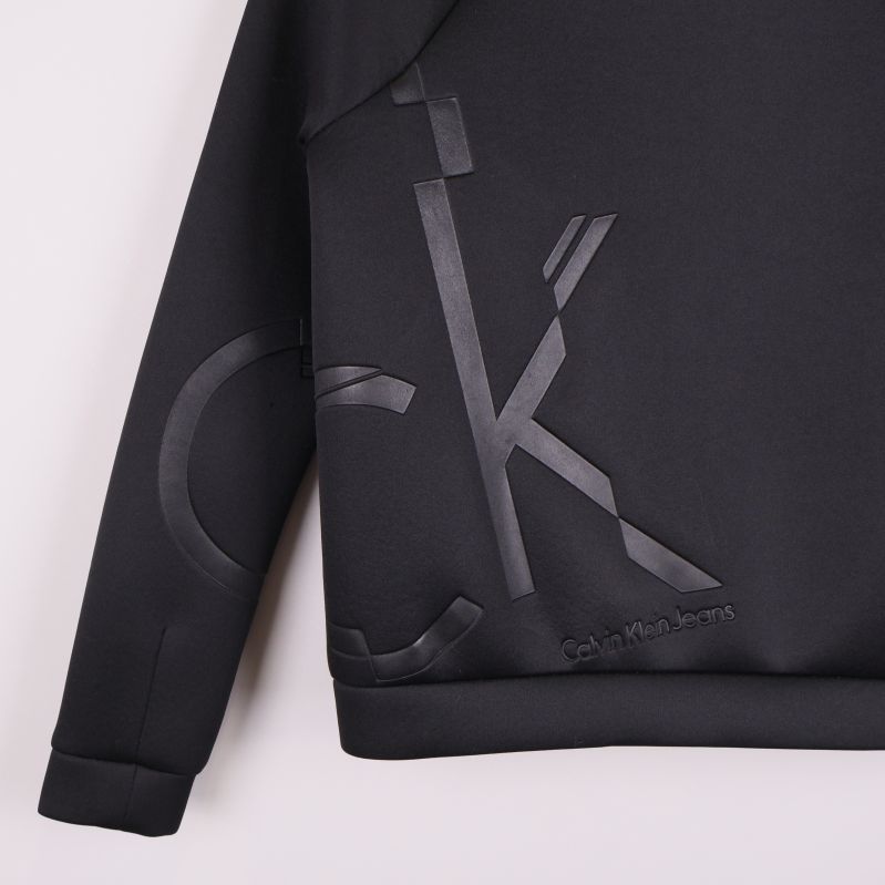 Närbild på blank CK-logga på svart jacka