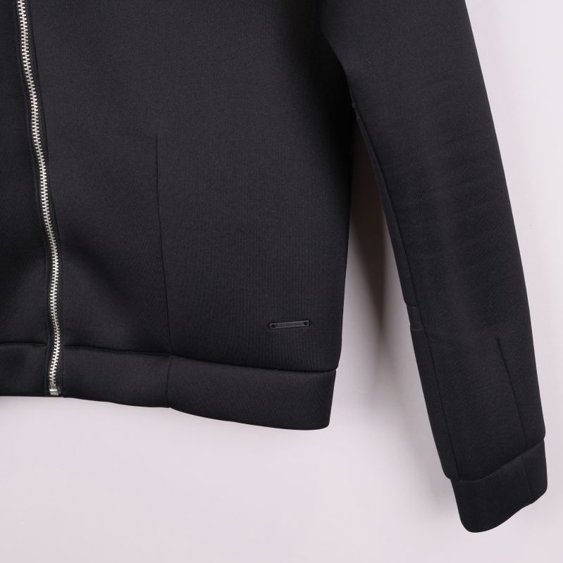 Närbild på ärm och nederkant av svart jacka