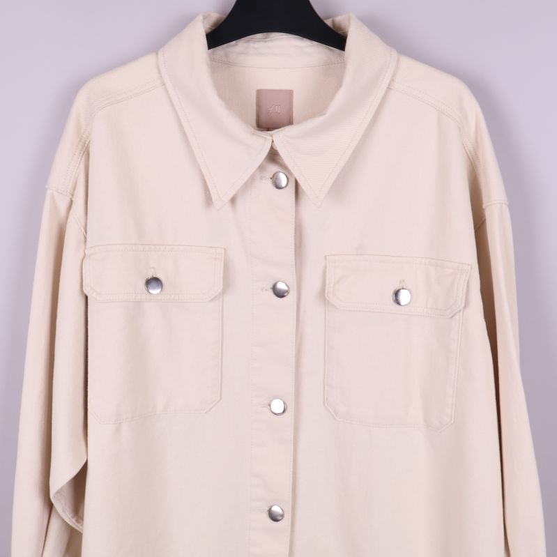 Närbild på övre delen och fickor av beige overshirt