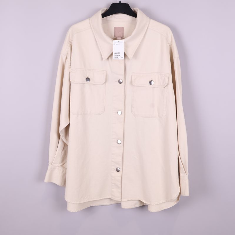 Framsidan av beige overshirt på galge med fickor