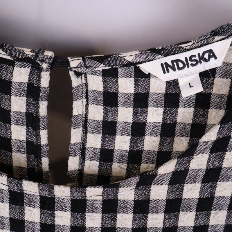 Närbild på Indiska-märkeslapp i halsen och rutmönster