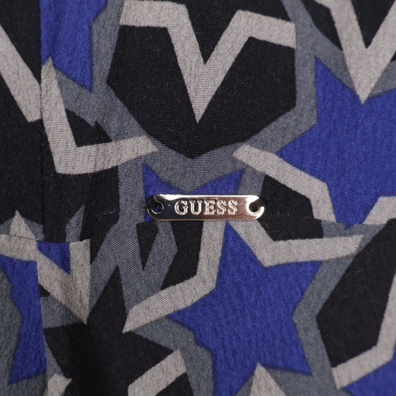 Metallbricka med Guess-loggan fastsatt på klänningens tyg