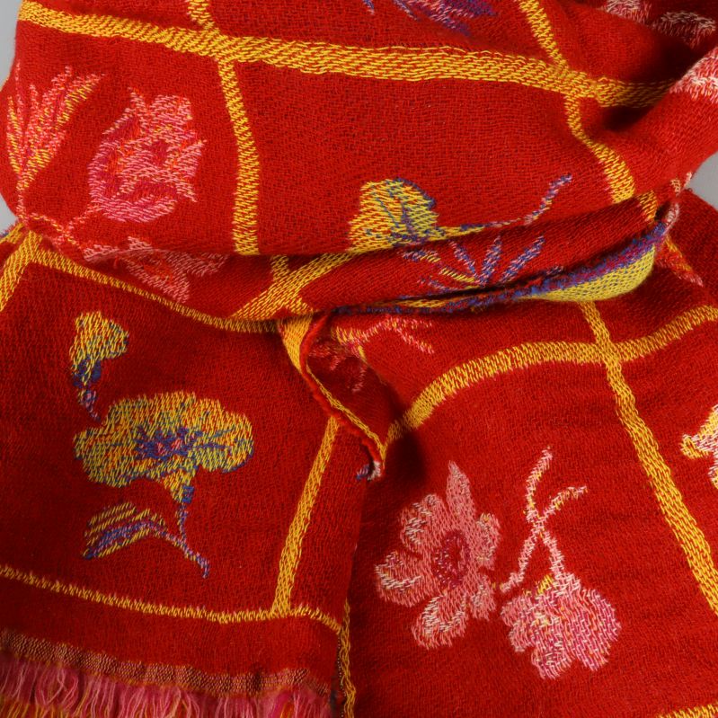 Närbild på rött tyg med rosa och gula blommor