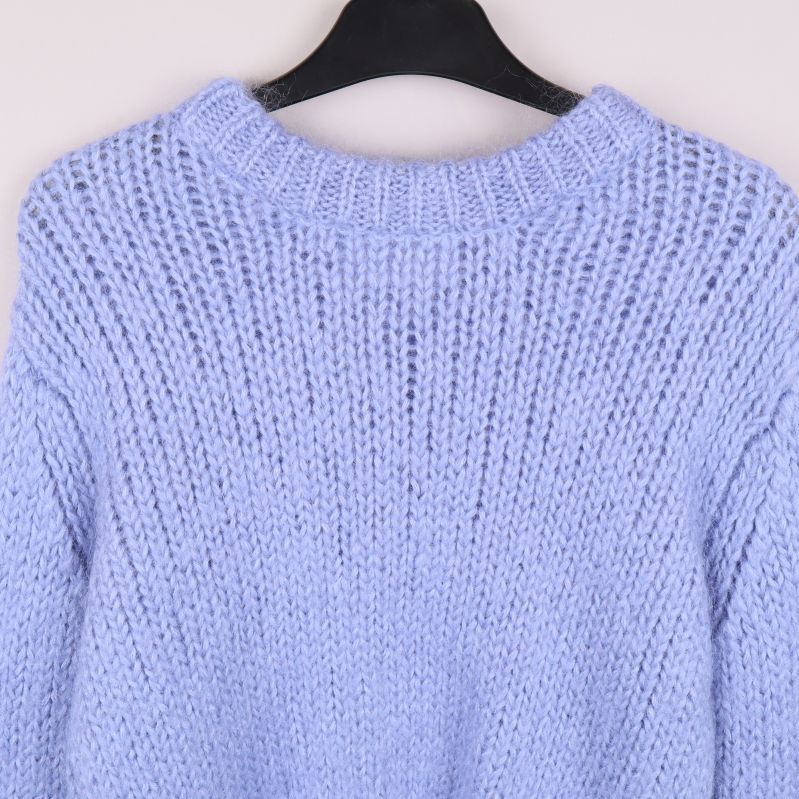 Närbild på hals och axlar på ljusblå stickad tröja