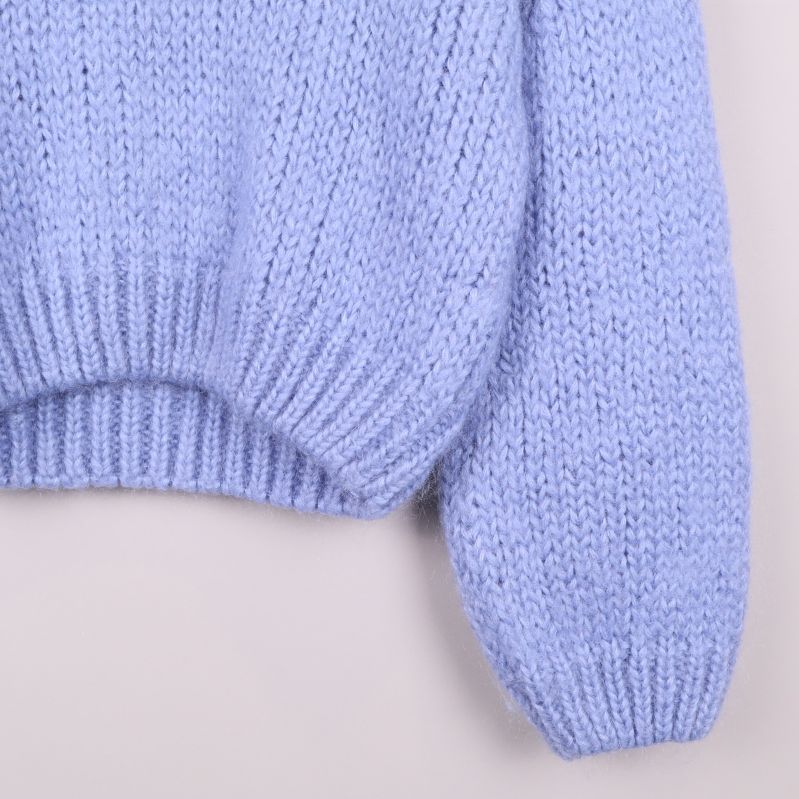 Närbild på tröjans stickade struktur och ärmslut