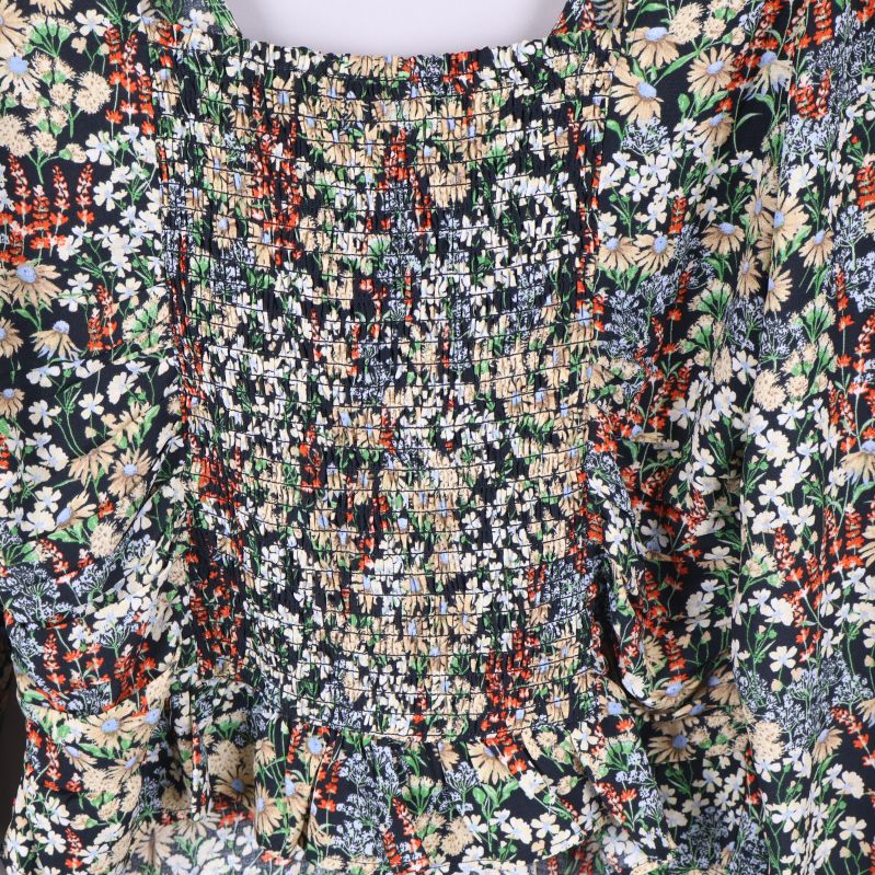 Närbild på smock och blommönster baktill på blus