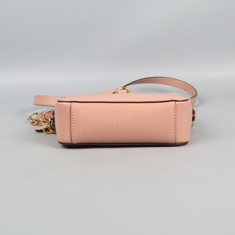 Botten av ljusrosa liten väska synlig