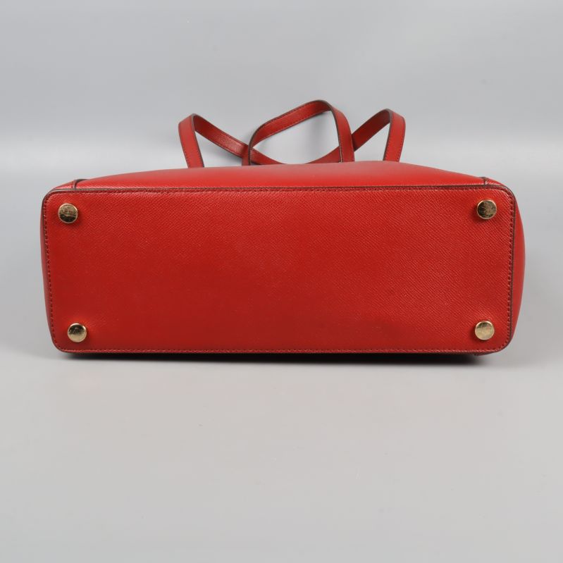 Undersida av röd axelväska med fyra metallfötter