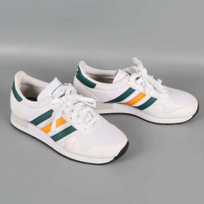 Sneakers från sidan som visar sidoränder i grönt och orange