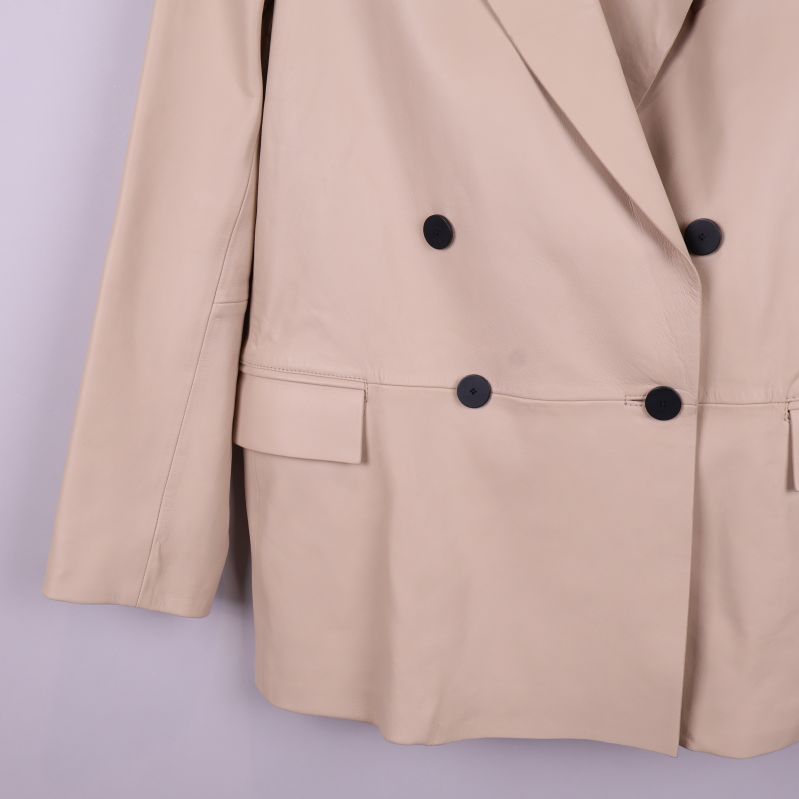 Detaljbild på knappslå och fickor på beige kavaj