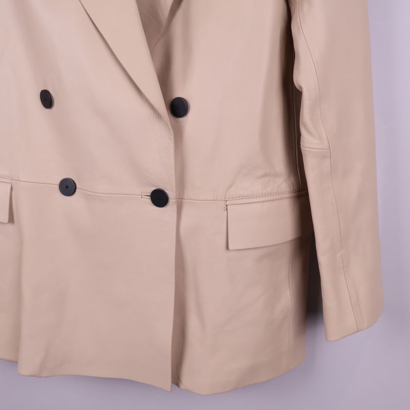 Närbild på fickdetalj på beige skinnkavaj