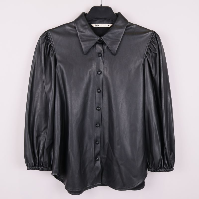 Svart konstläderblus med puffärmar sedd framifrån