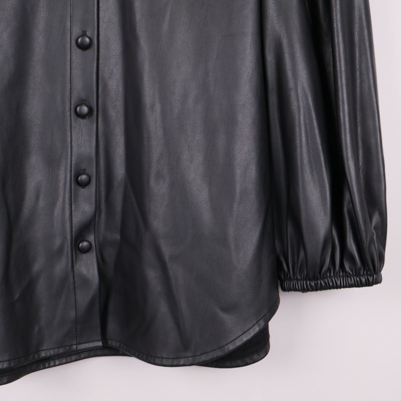 Närbild på knappslå och nedre kanten av svart blus