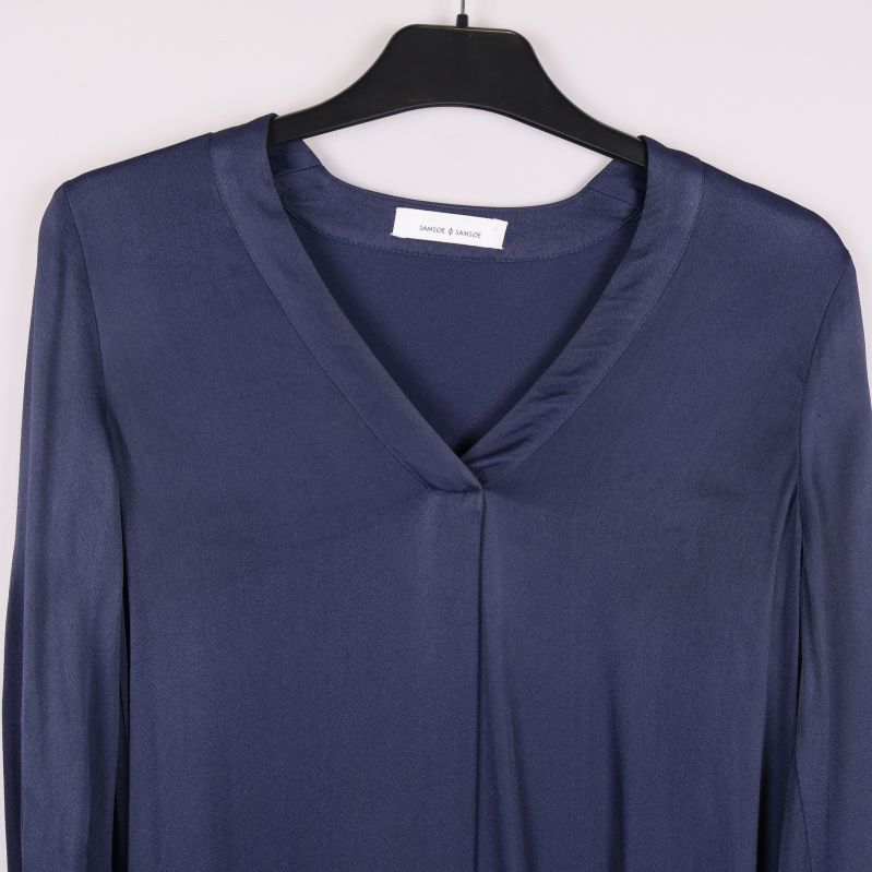 Närbild på v-ringning och axelparti av blå klänning