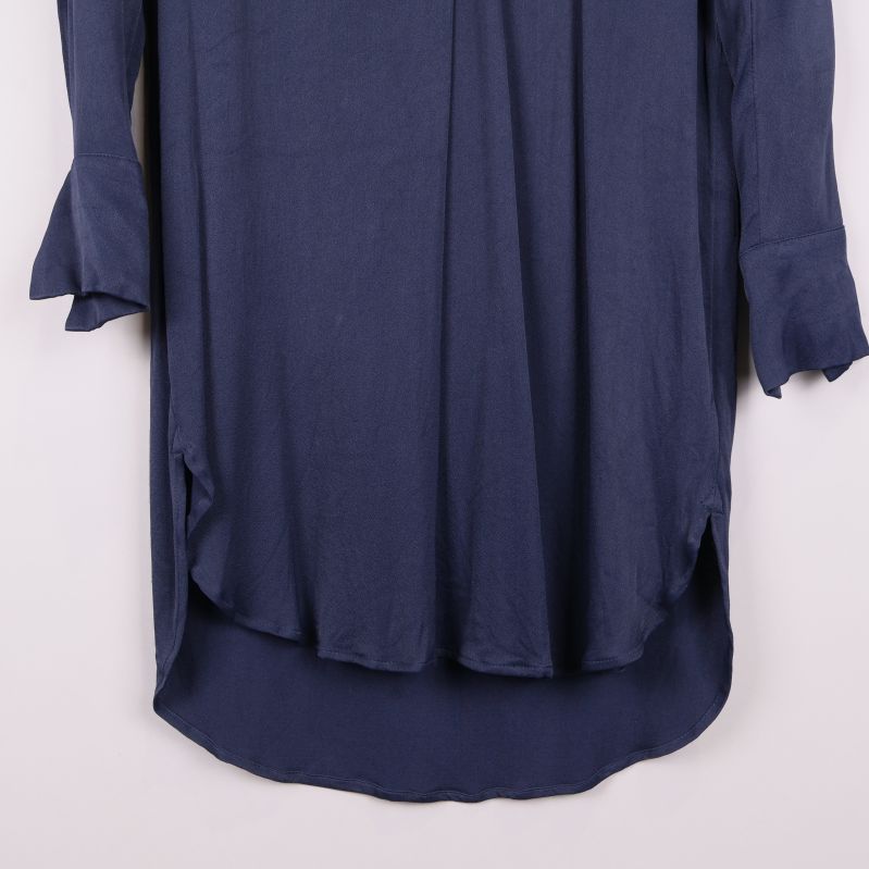 Nederkant och ärmslut på blå klänning i närbild