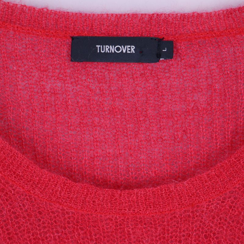 Närbild på etikett med TURNOVER-logga i halsen