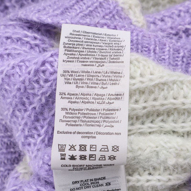 Materialetikett med procenthalt av ull, alpacka och polyester i tröjan