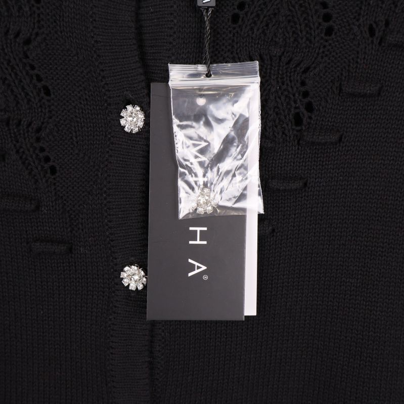 Koftans etikett och extra knapp i plastpåse