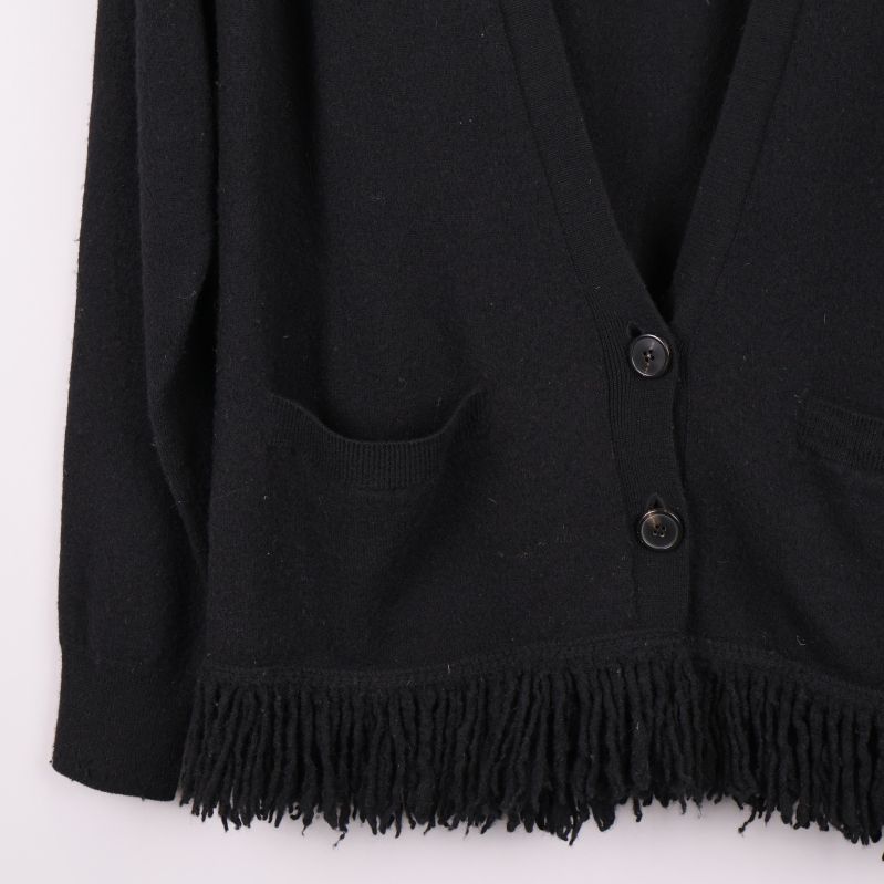 Närbild på fransar och fickor på koftan