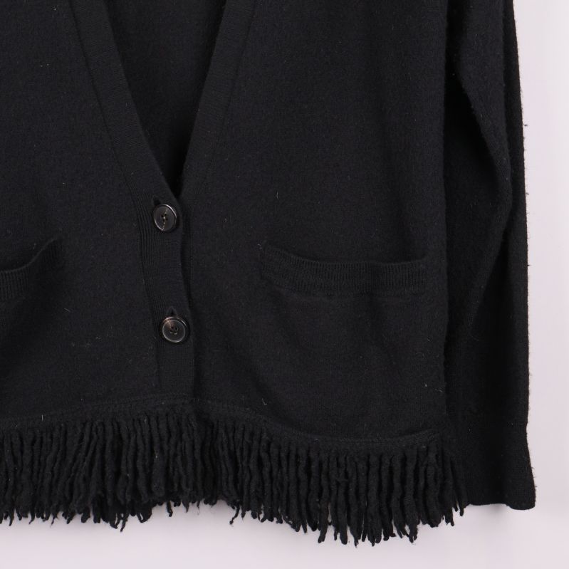 Detalj på ficka och fransar på svart kofta