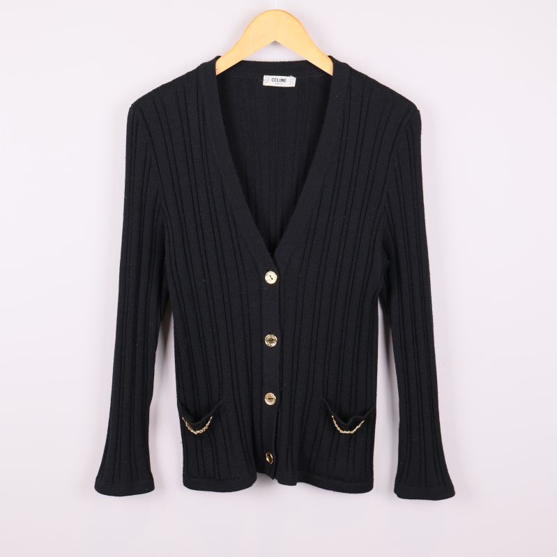 Svart ribbstickad kofta på galge med guldknappar