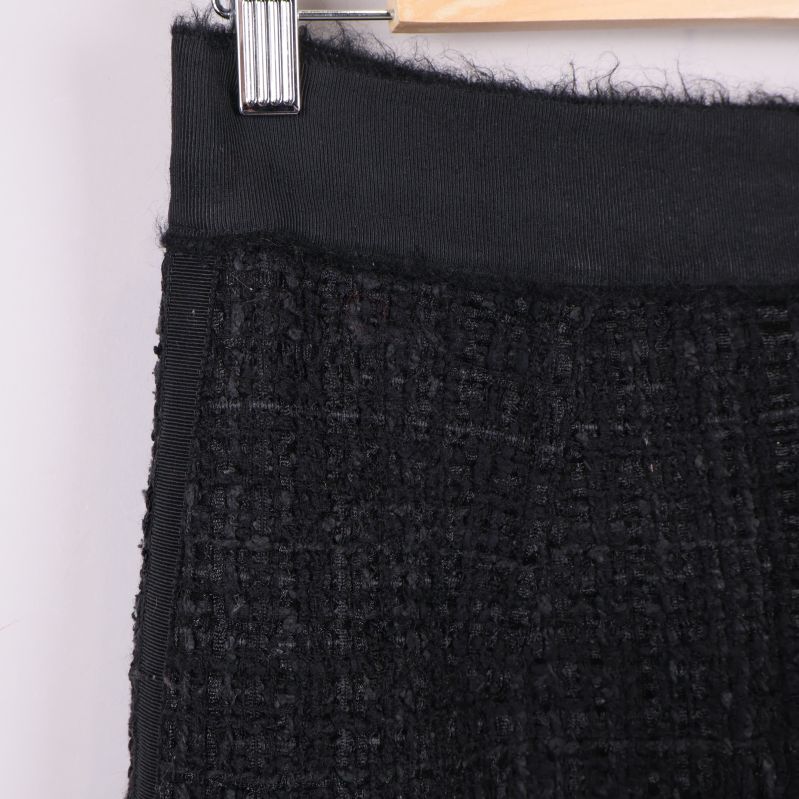Detaljbild på midjebandet av svart kjol i boucléstruktur
