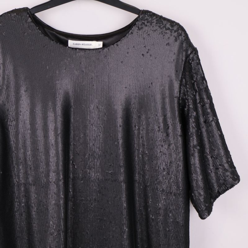 Detaljbild på framstycke med täta svarta paljetter