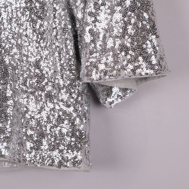 Närbild på paljetter och ärmslut av toppen