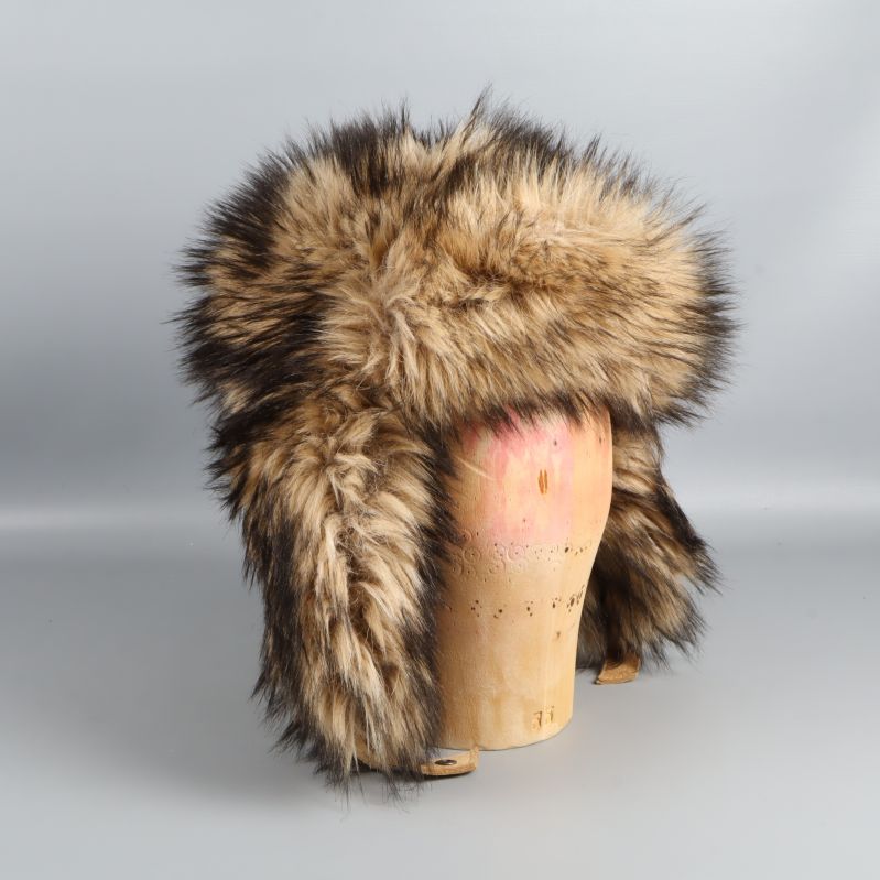 Fuskpälsmössa på trähuvud fotograferad från snett framifrån