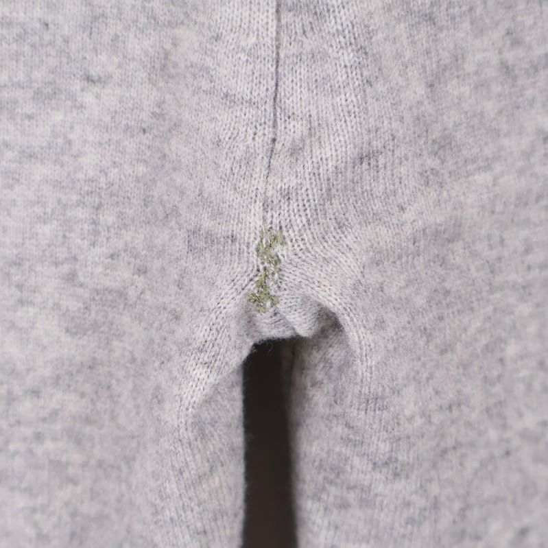 Närbild på lagad söm i grenen på grå byxa