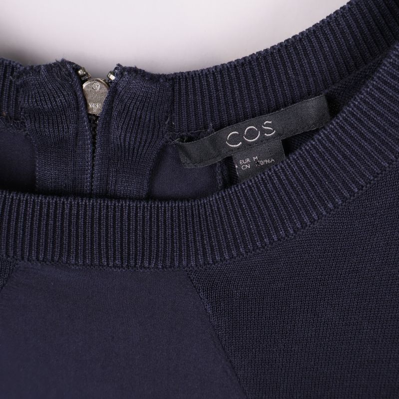 Närbild på halsringning och COS-märketikett