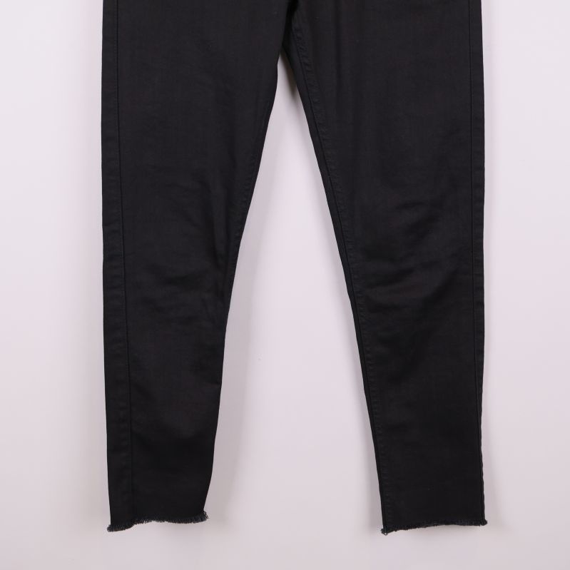 Närbild på benslut med rå kant på svarta jeans