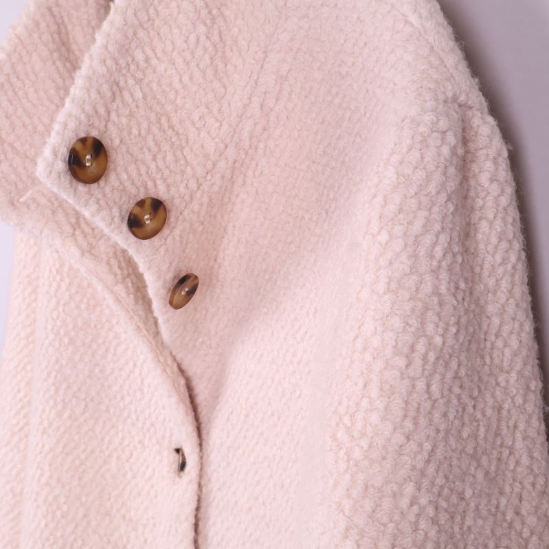 Närbild på kappans struktur och knappar från sidan