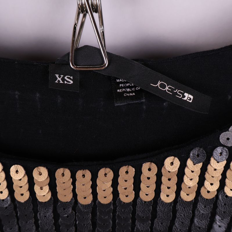 Storleks- och märkesetikett samt halsringning på paljettopp