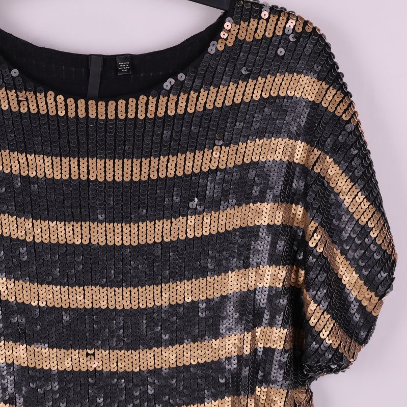 Närbild på axel och paljettränder samt struktur på toppen